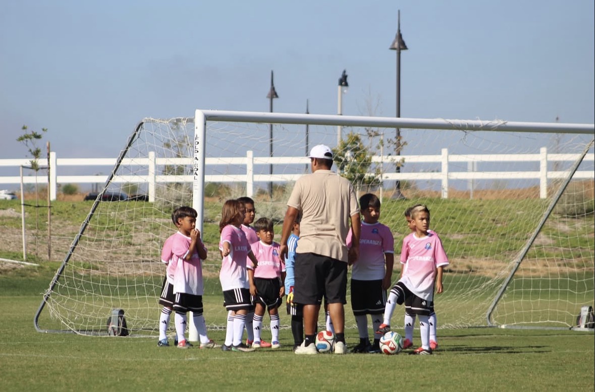 Young La Esperanza players gathered with their coach in front of the goal
