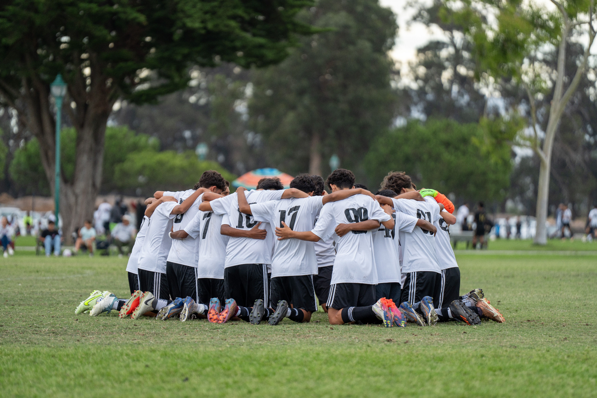 La Esperanza team kneeling together in a pregame huddle