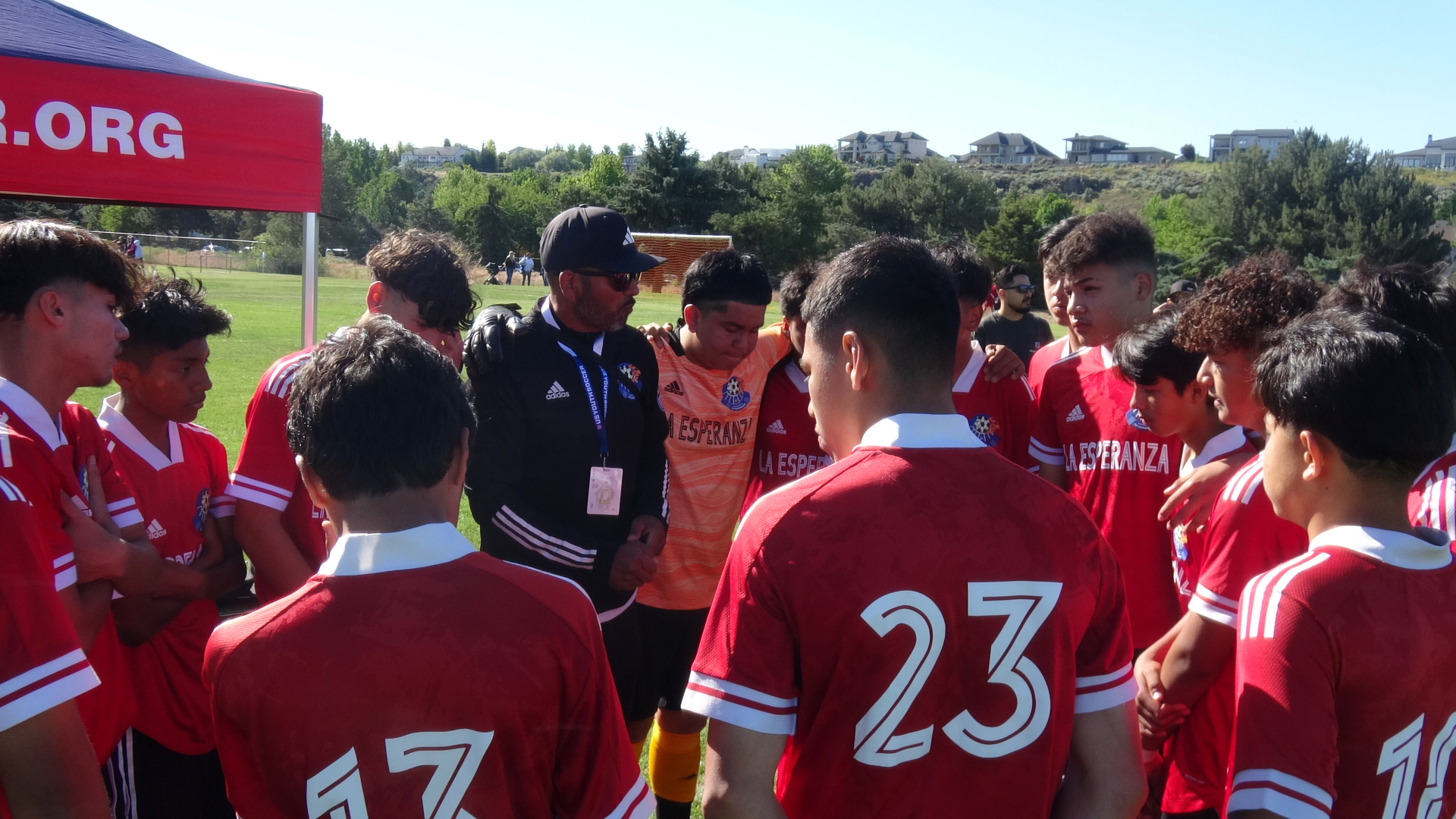 La Esperanza team in red listening to the coach